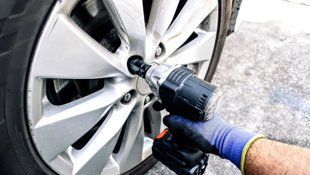 auto mechanic using impact wrench cordless to change car