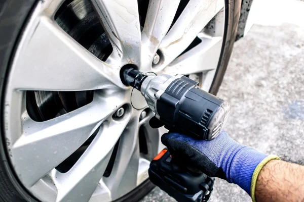 auto mechanic using impact wrench cordless to change car